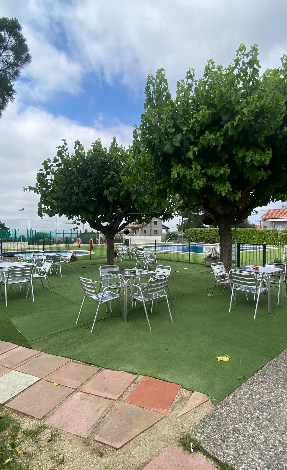 El jardi del club, amb taules a l'ombra dels arbres